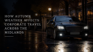 A dark executive saloon with its headlights on waits on a rain-soaked city street lined with autumn trees, illustrating how autumn weather affects corporate travel across the Midlands.